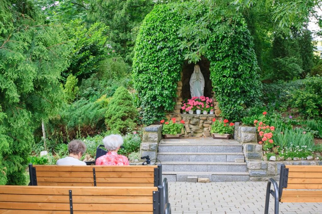 zahrada s lavičkami u sochy Panny Marie